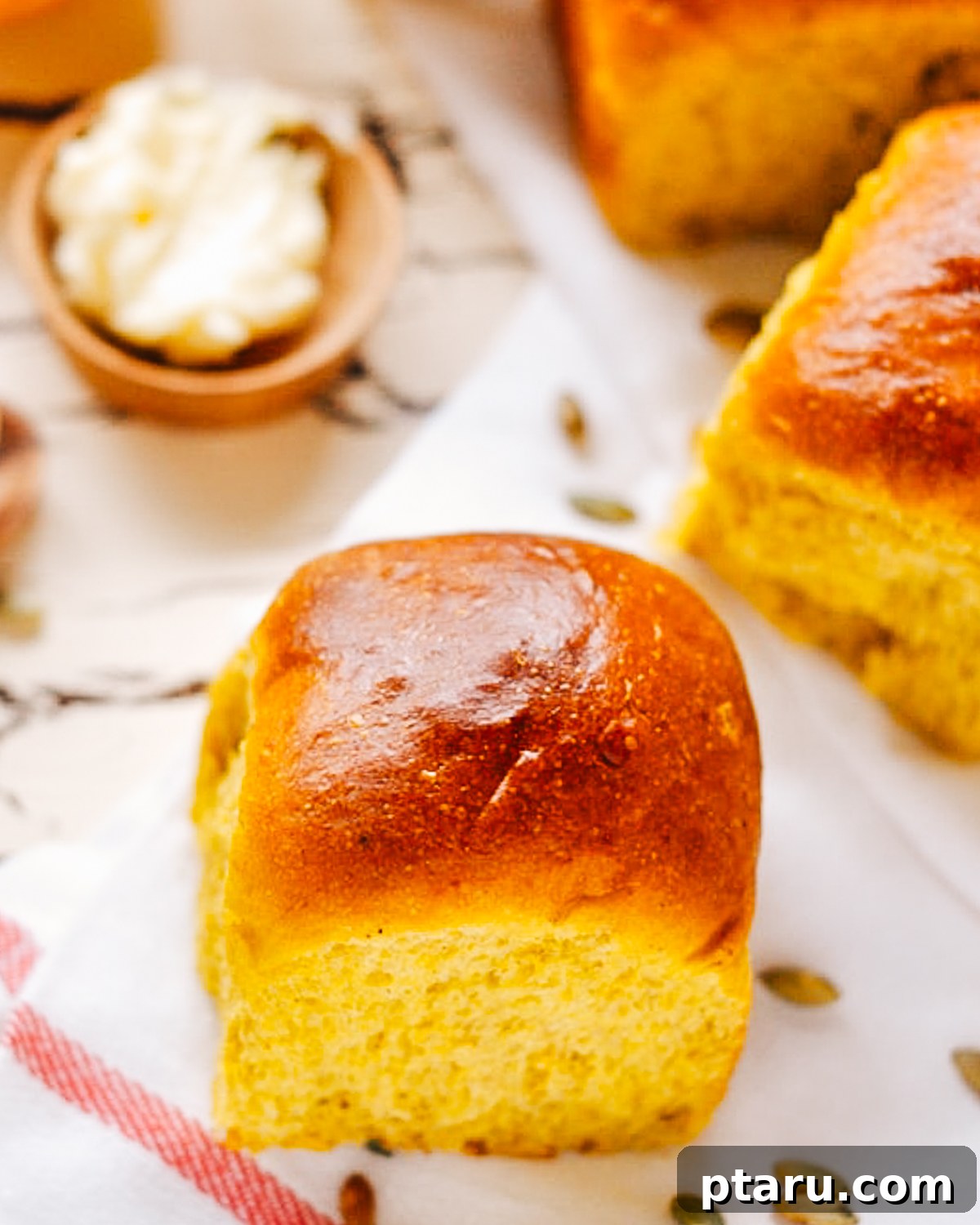Golden Pumpkin Dinner Rolls 4 A close-up of a single pumpkin dinner roll, showcasing its soft interior and golden exterior.