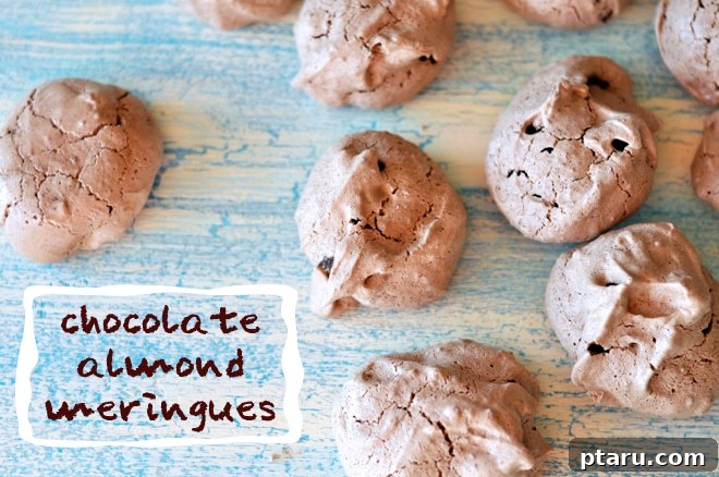 Dreamy Chocolate Almond Kisses 5 A hand reaching for a chocolate almond meringue from a baking tray.