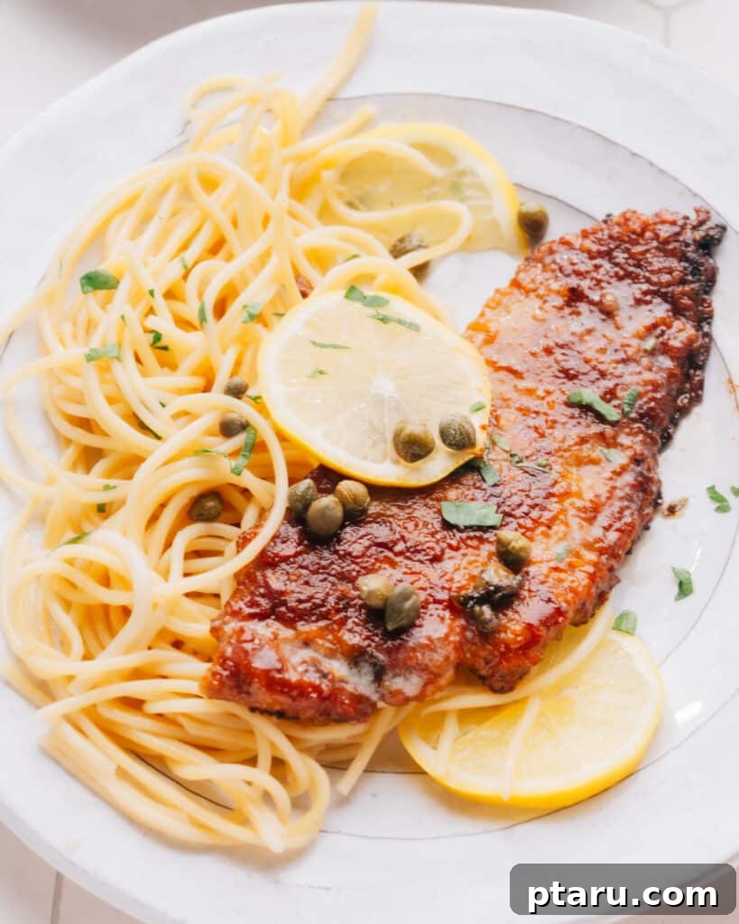 Veal Scallopini with Zesty Lemon Caper Sauce 2 Veal Scallopini on a bed of spaghetti with lemon slices.