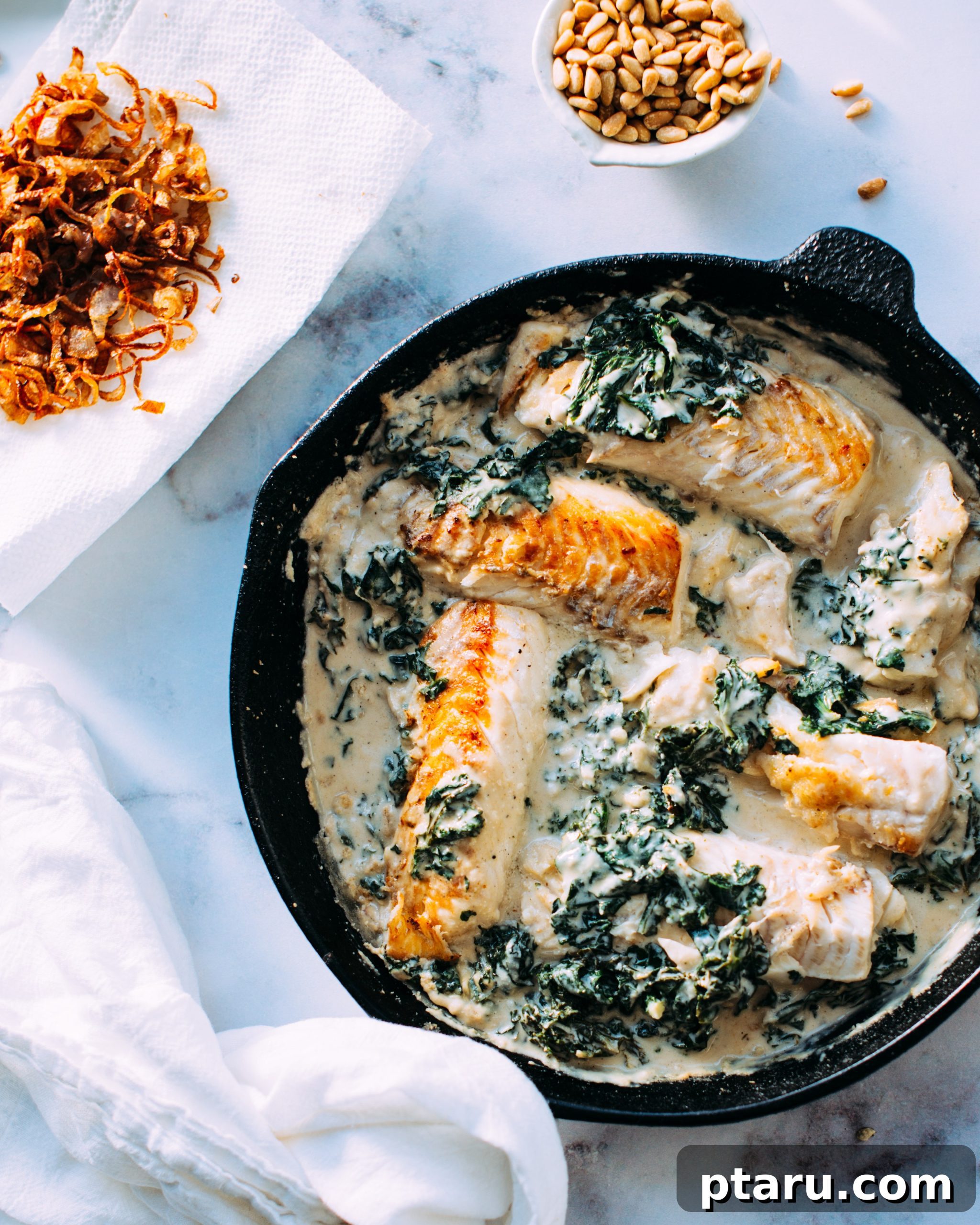 Fish and Kale in Tahini Sauce A beautifully plated dish of seared white fish with wilted kale, drizzled with creamy tahini sauce and topped with crispy shallots.