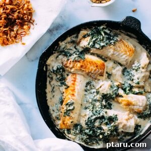 Fish and Kale Recipe An overhead shot of a prepared dish of fish and kale in tahini sauce, garnished with crispy shallots and pine nuts.
