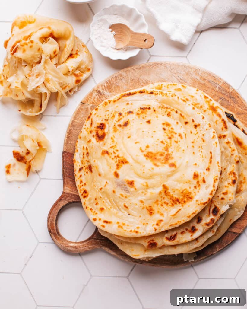 Paratha Golden Layered Indian Flatbread 2 Paratha on a board with some showing their flaky layers