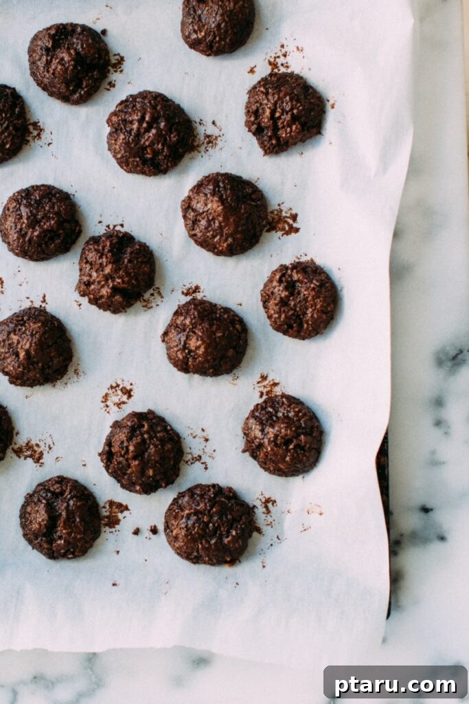 Fudgy Chocolate Coconut Cookies 3 Chocolate coconut cookies baked and cooling on a parchment-lined baking tray, showing their golden edges and fudgy centers.