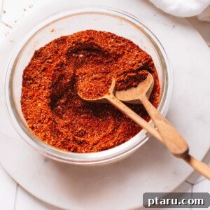 Homemade chili seasoning in a glass container with spoons.
