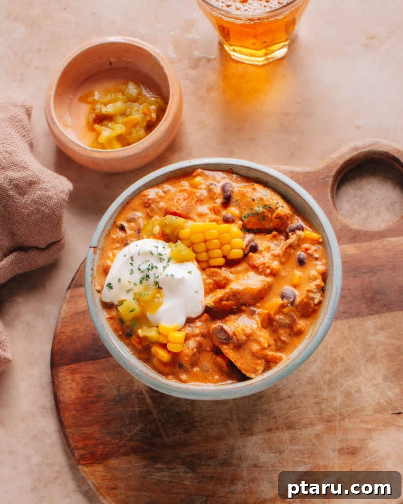 Homemade Chili Spice Blend 3 The cream cheese chicken chili is in a bowl and is topped with corn kernels, chilies, and cream cheese.