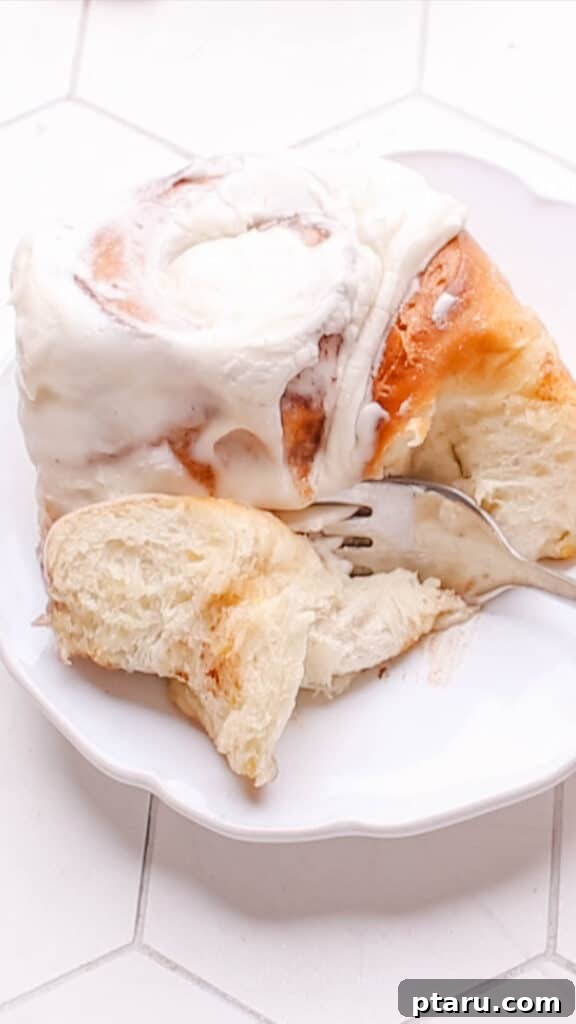 Sweet Cinnamon Raisin Swirls 3 A fork cutting into a soft cinnamon raisin roll, revealing its gooey center.