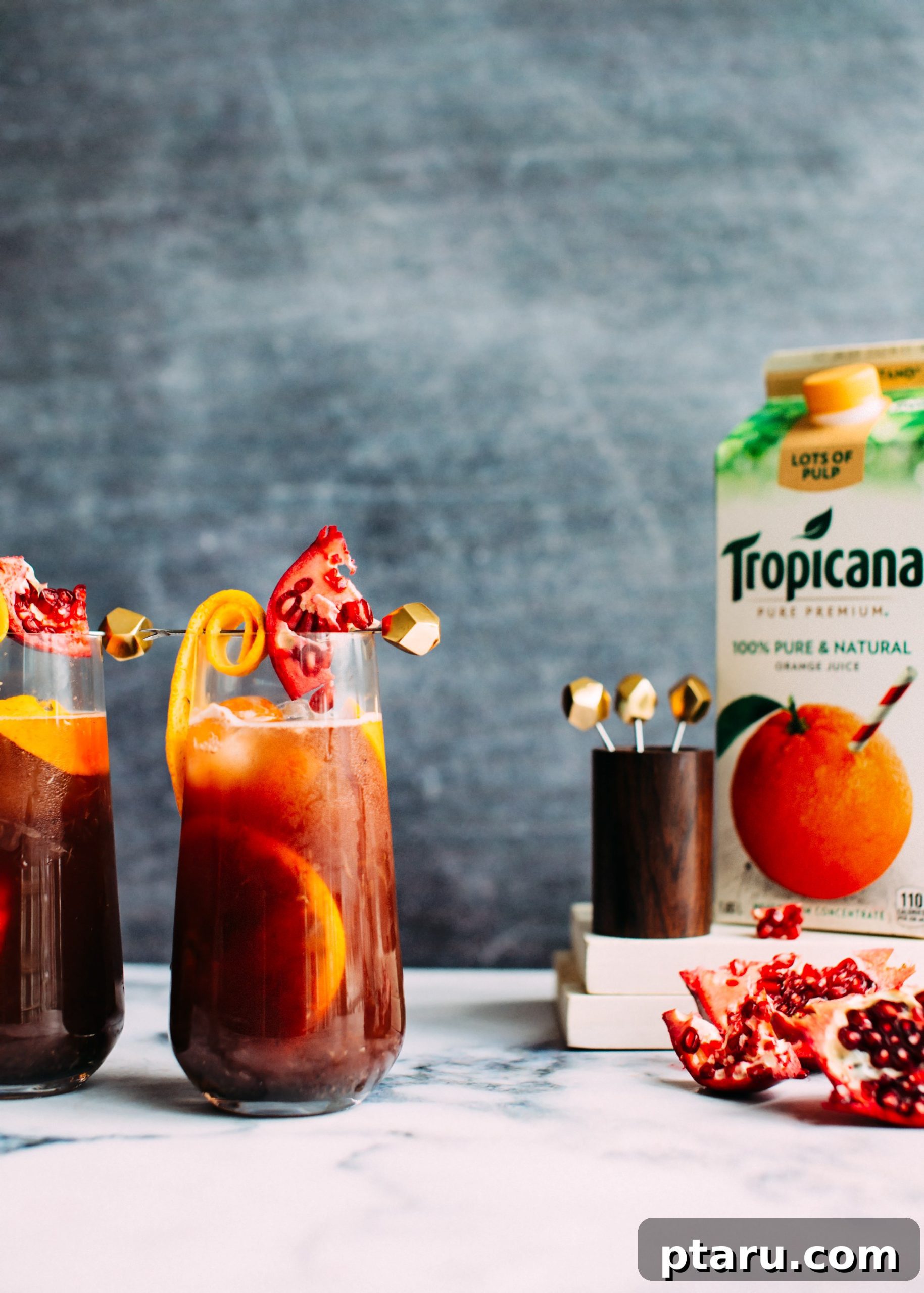 Festive Christmas Sangria 4 A collection of Christmas Sangria ingredients including a bottle of red wine, orange juice, fresh oranges, and whole spices.