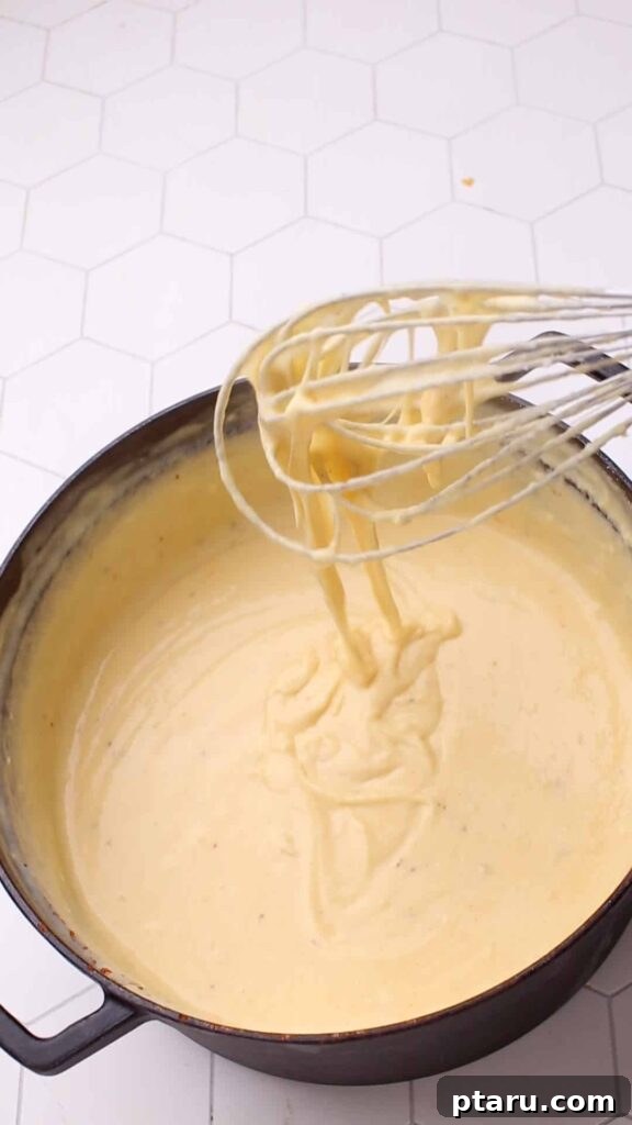 Mac and Cheese Perfection: The Ultimate Golden Sauce 12 Whisking cheese sauce for mac and cheese.
