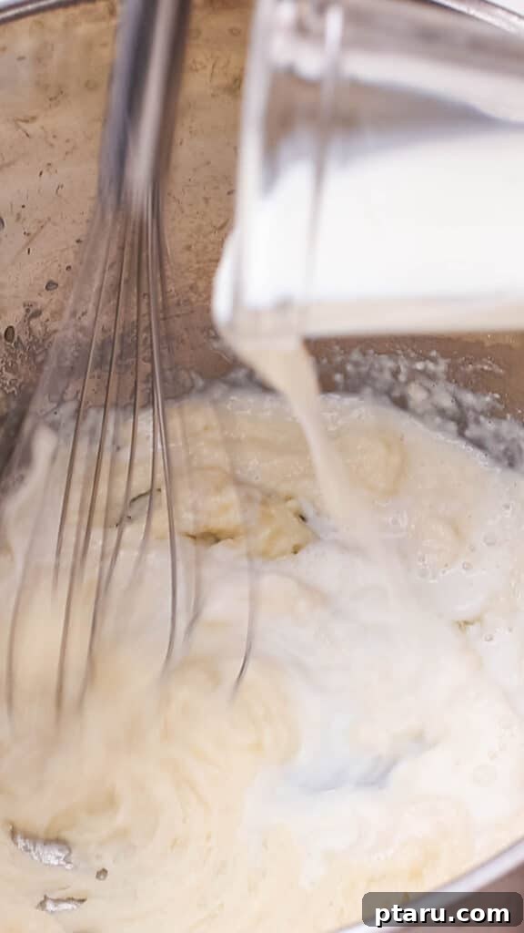 Mac and Cheese Perfection: The Ultimate Golden Sauce 7 Adding milk to butter and flour mixture in saucepan.