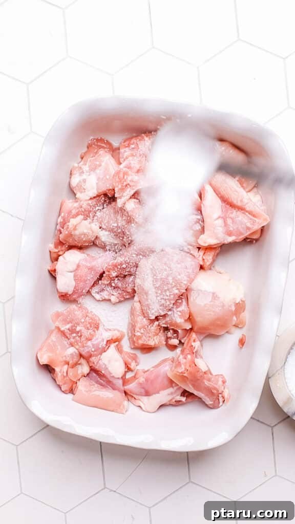 Your New Favorite Quick Coconut Curry Chicken 5 Seasoning cubed chicken breast with salt on a cutting board before adding it to the curry, enhancing flavor and tenderness.