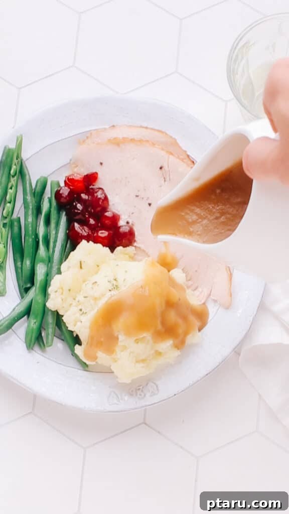 Easy Turkey Giblet Gravy No Drippings 3 Rich, homemade giblet gravy being poured over a classic Thanksgiving plate with mashed potatoes and turkey.