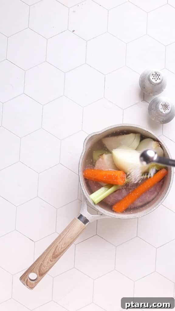 Easy Turkey Giblet Gravy No Drippings 5 Adding kosher salt to turkey giblets and vegetables in a saucepan for broth.