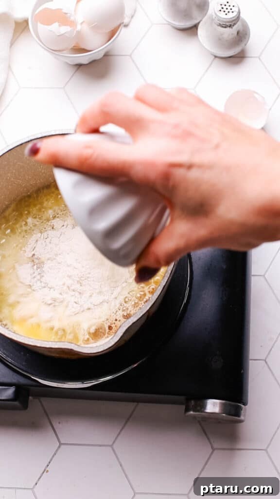 Easy Turkey Giblet Gravy No Drippings 7 All-purpose flour being added to melted butter in a saucepan, forming a roux for gravy.