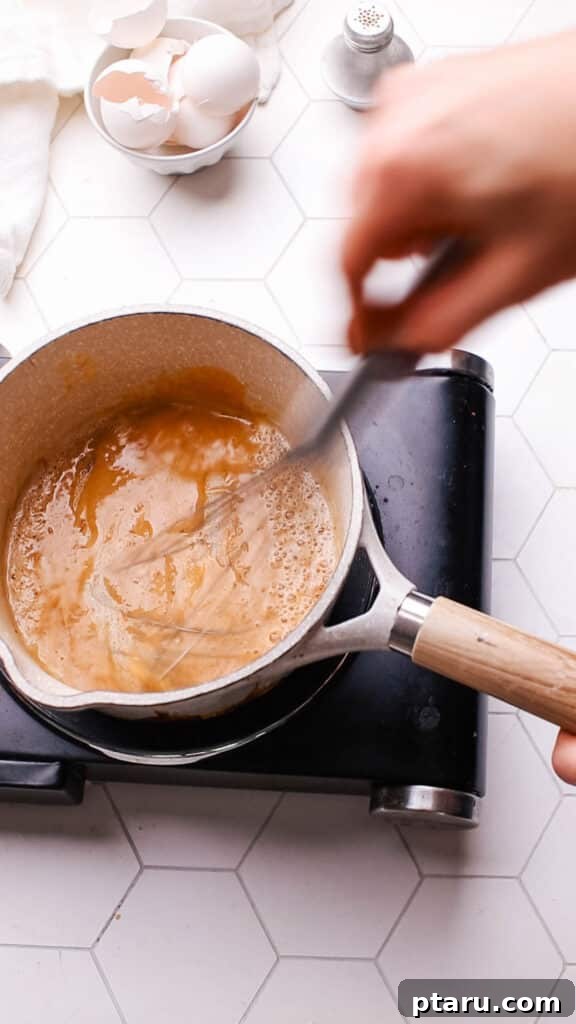 Easy Turkey Giblet Gravy No Drippings 8 Adding strained turkey broth to the caramel-colored roux in a saucepan, whisking to combine for a smooth gravy.