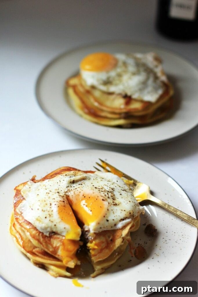 Rise and Shine: 23+ Sausage and Egg Breakfast Ideas 20 A mouth-watering stack of Sausage Pancakes topped with a runny fried egg and a drizzle of black pepper syrup.