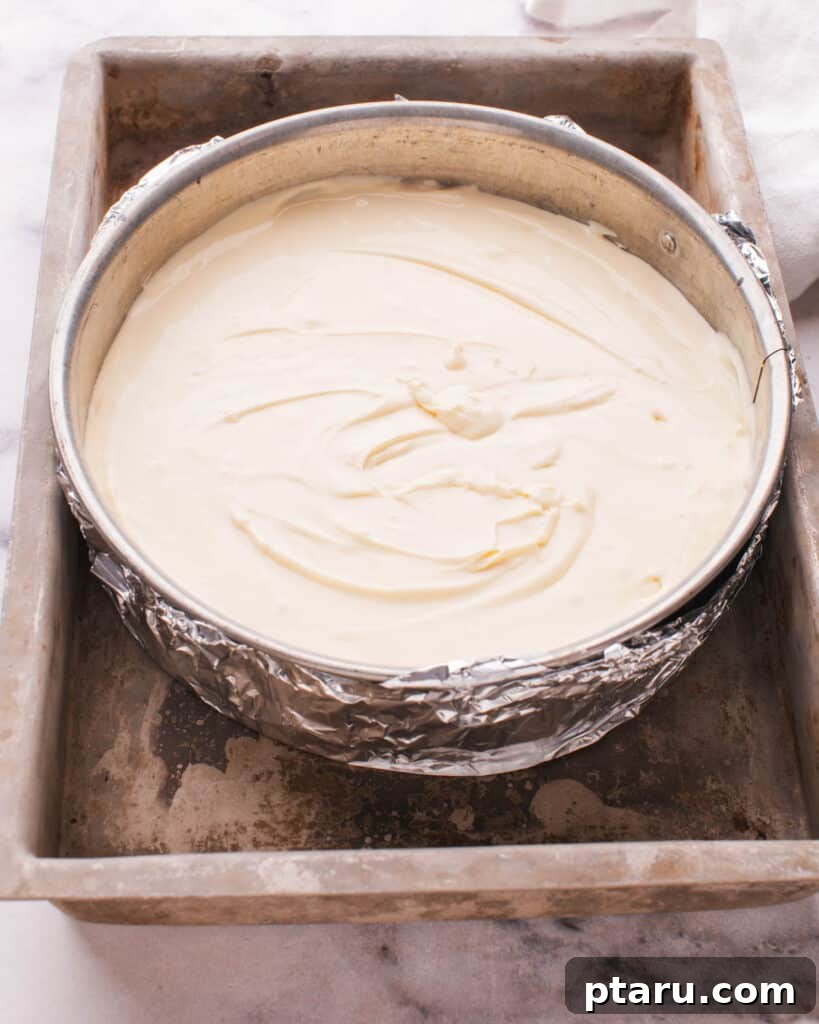 The Ultimate Philadelphia Cheesecake Guide 14 Springform pan wrapped in heavy-duty foil, placed inside a larger roasting pan for a water bath setup