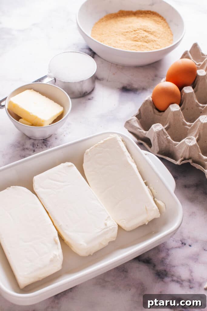 The Ultimate Philadelphia Cheesecake Guide 3 Ingredients laid out for Philadelphia Cheesecake preparation, including cream cheese, sugar, eggs, and graham crackers