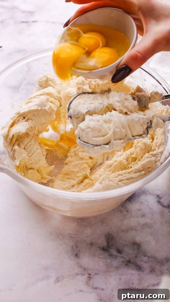 The Ultimate Philadelphia Cheesecake Guide 8 Adding eggs one by one to the creamy Philadelphia cheesecake filling mixture