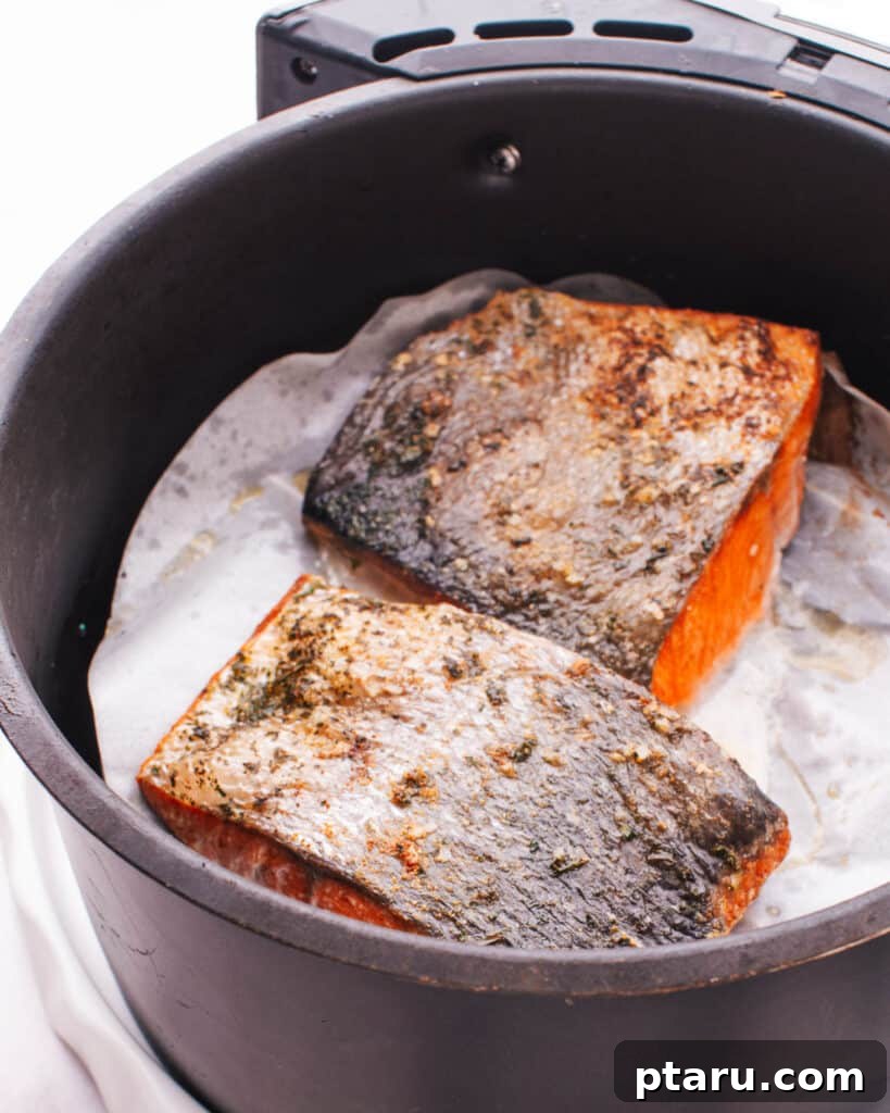 Perfectly Moist Flaky Air Fryer Frozen Salmon 3 Crispy Air Fried Salmon fillet resting in an air fryer basket.