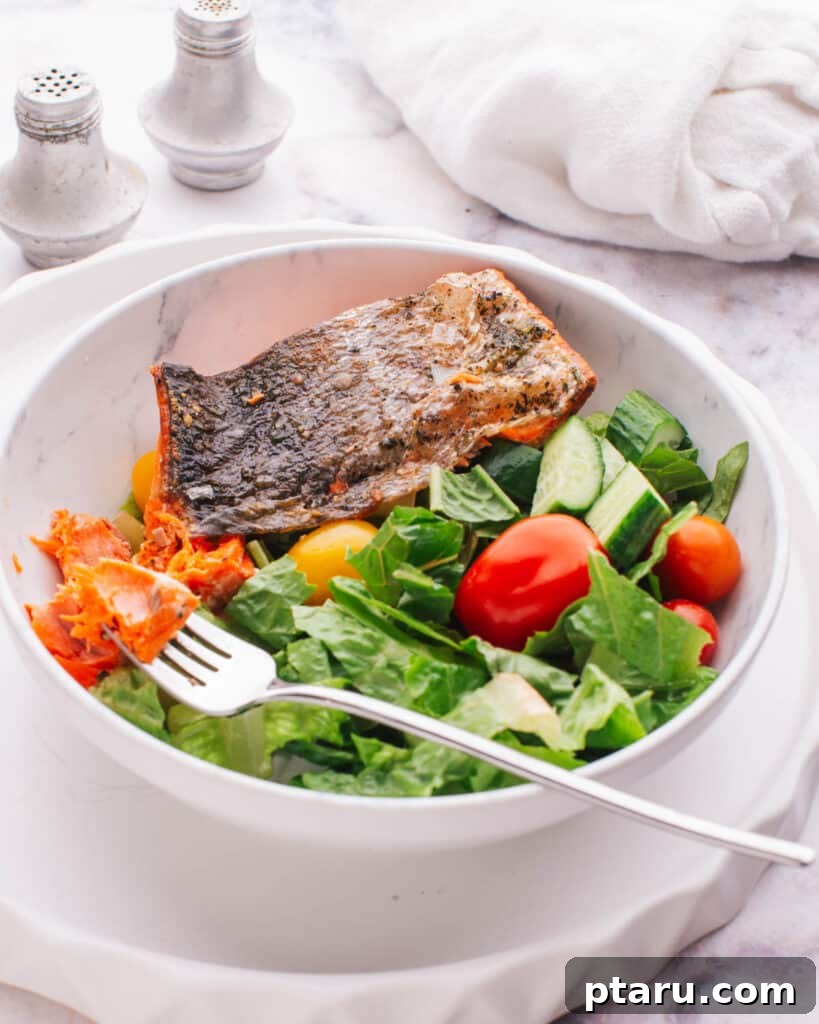 Perfectly Moist Flaky Air Fryer Frozen Salmon 9 Air fryer frozen salmon fillet, flaked over a vibrant salad with mixed greens and other vegetables.