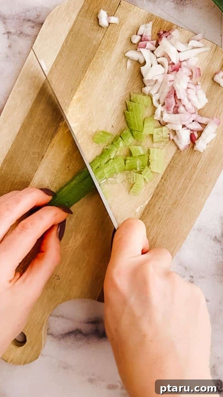 Flavorful Curried Chicken Salad with Sweet Grapes 5 A cutting board with freshly chopped celery and red onion, essential components for adding crunch and flavor to the chicken salad.