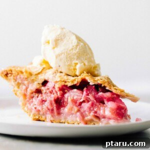 A slice of strawberry rhubarb pie with ice cream.