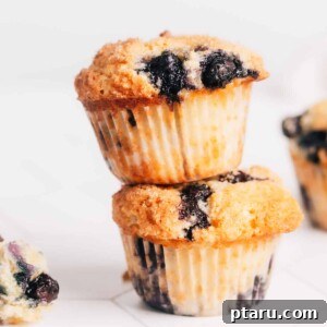 A stack of golden-brown Lemon Blueberry Sour Cream Muffins, showcasing their fluffy texture and delicious appearance, ready to be served.