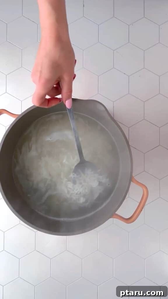 My Indian Mother-in-Laws Foolproof Basmati Rice 5 A fork gently mixing basmati rice in a pot after cooking, showing its fluffy texture.