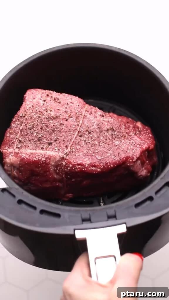 Melt in Your Mouth Air Fryer Roast Beef 5 Placing seasoned beef into the air fryer basket