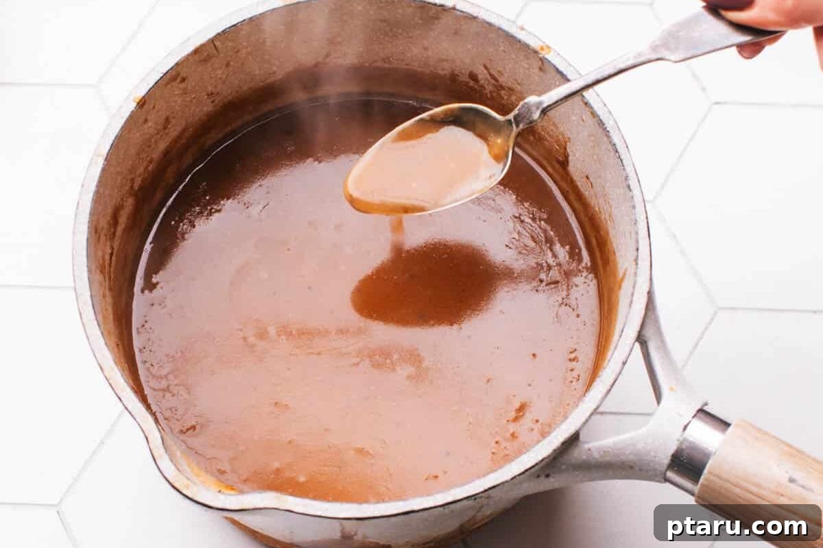 Melt in Your Mouth Air Fryer Roast Beef 7 Velvety smooth brown gravy in a pot with a spoon, ready to serve.