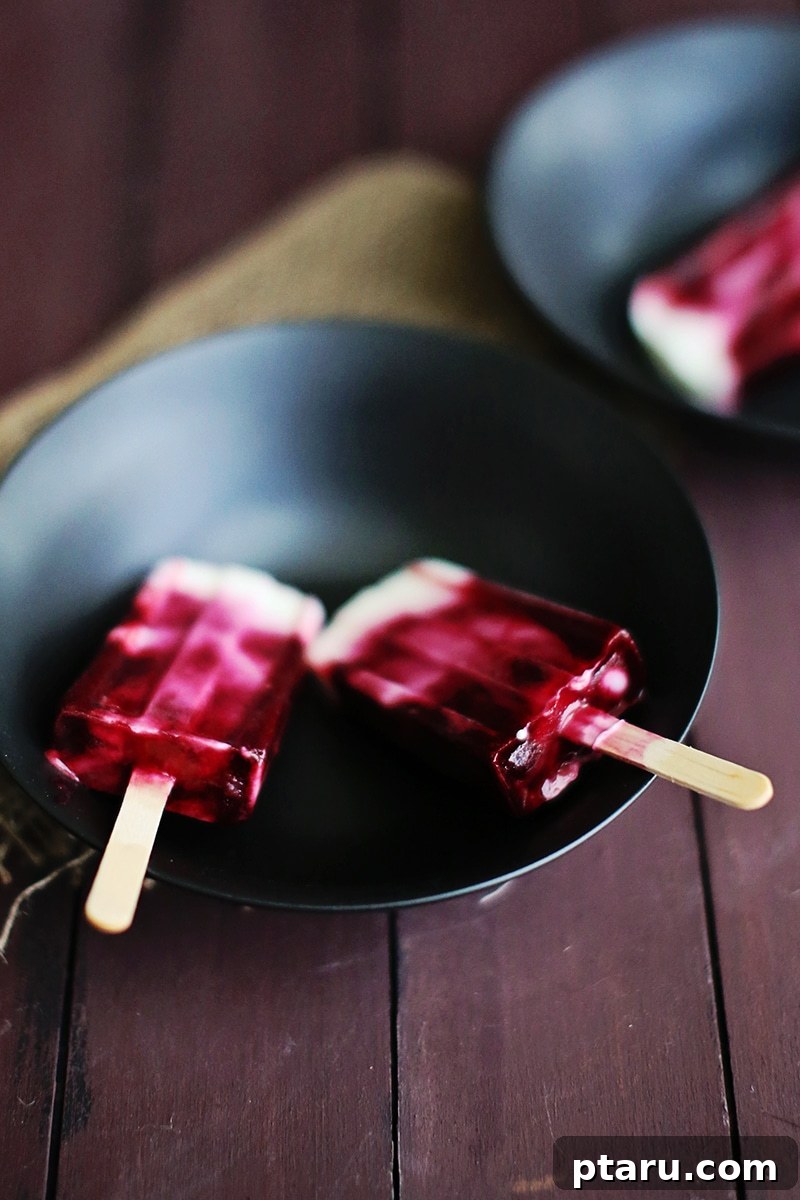 Creamy Blackberry Swirl Fro-Yo Pops 4 Several homemade raspberry yogurt popsicles neatly arranged in a sleek, modern popsicle mold, illustrating the ease of making them.