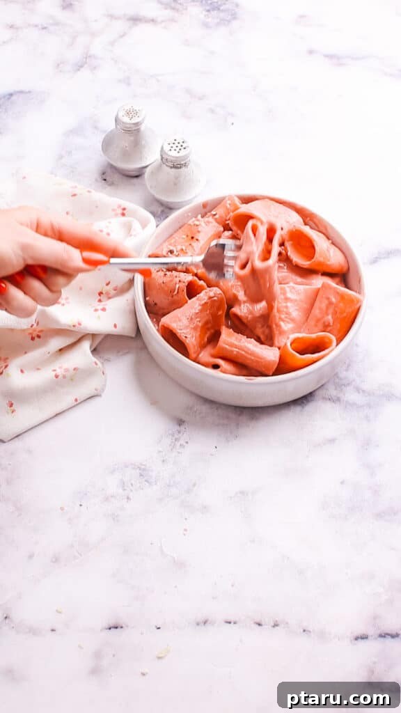 Velvety Beet Pasta Sauce 12 Taking a spoonful of pasta with beet pasta sauce from a bowl.