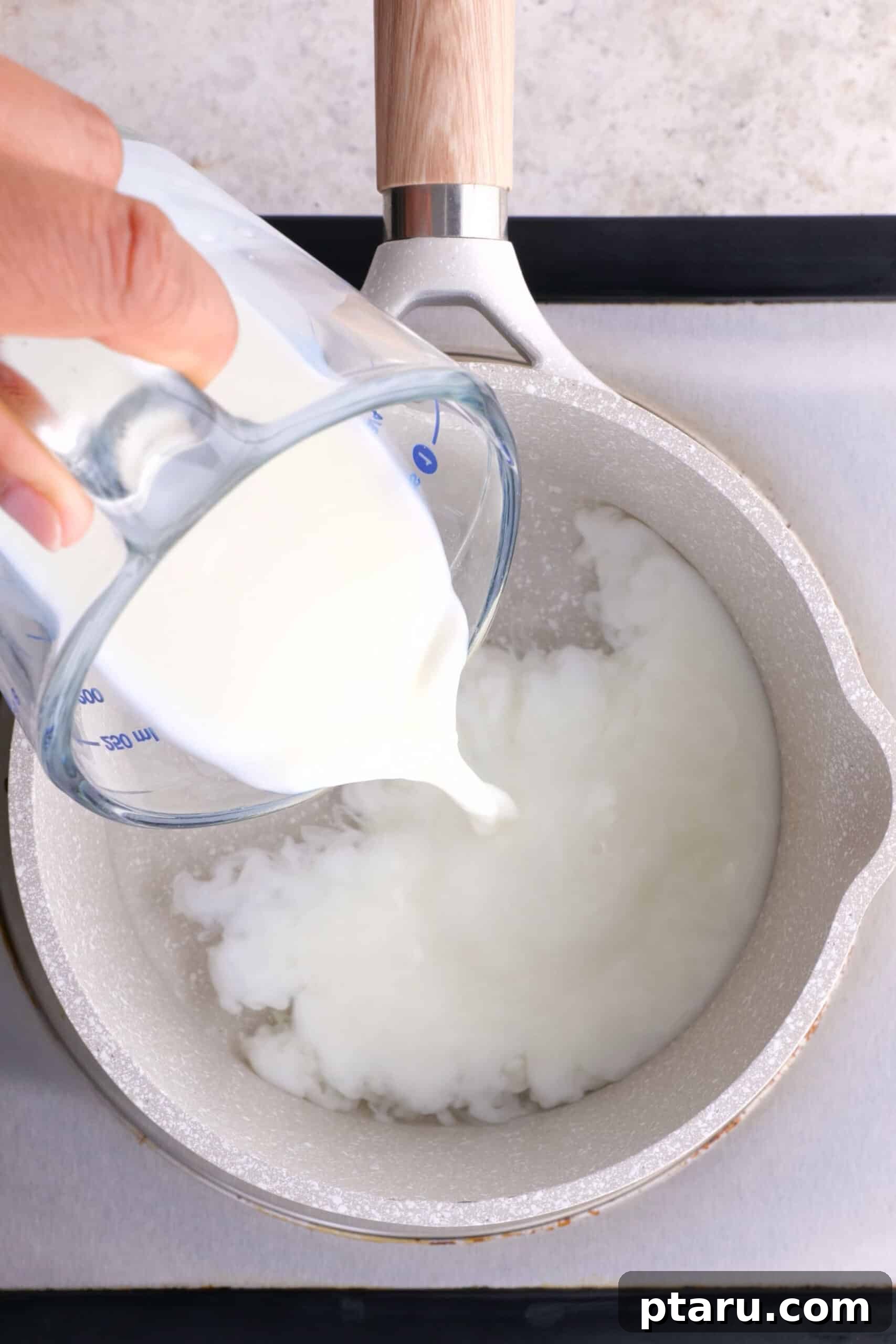 Secrets to Authentic Indian Masala Chai 3 Pouring whole milk into a saucepan of hot water, symbolizing the initial step of making homemade chai.