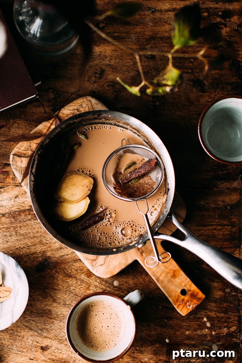 Secrets to Authentic Indian Masala Chai 7 A freshly brewed pot of authentic Indian chai tea from scratch, with a whole cinnamon stick visible, ready to be served.