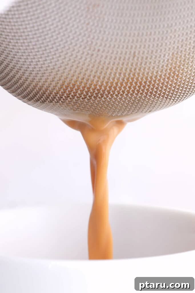 Secrets to Authentic Indian Masala Chai 8 Filtering the brewed chai tea to remove tea granules and whole spices, ensuring a smooth drink.