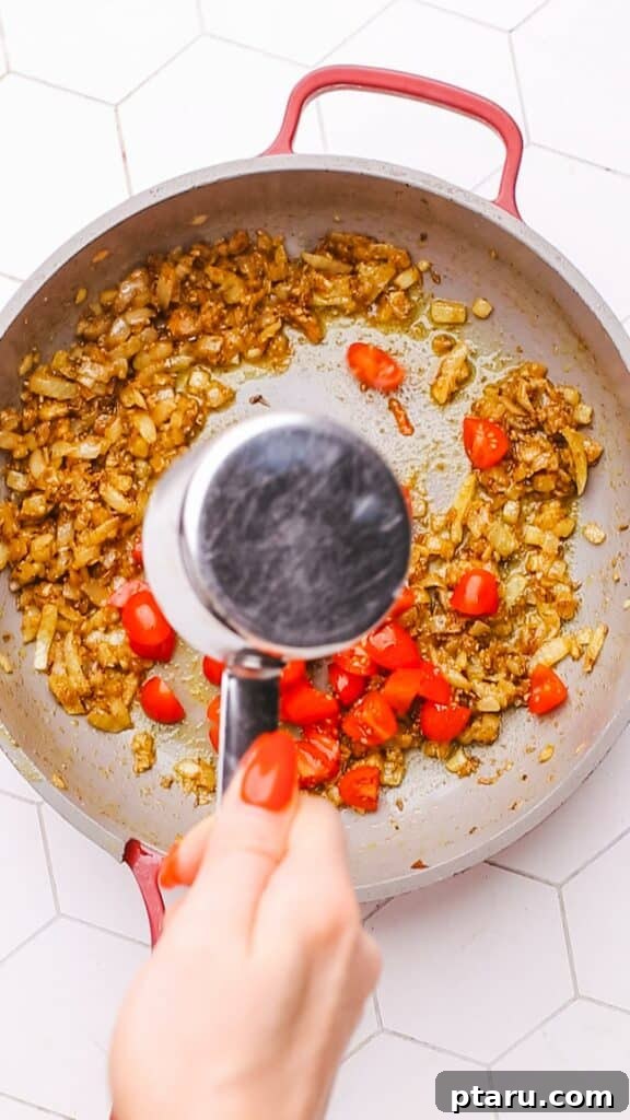 Creamy Spinach Paneer 7 Adding diced tomatoes to the sautéed onion and spice mixture