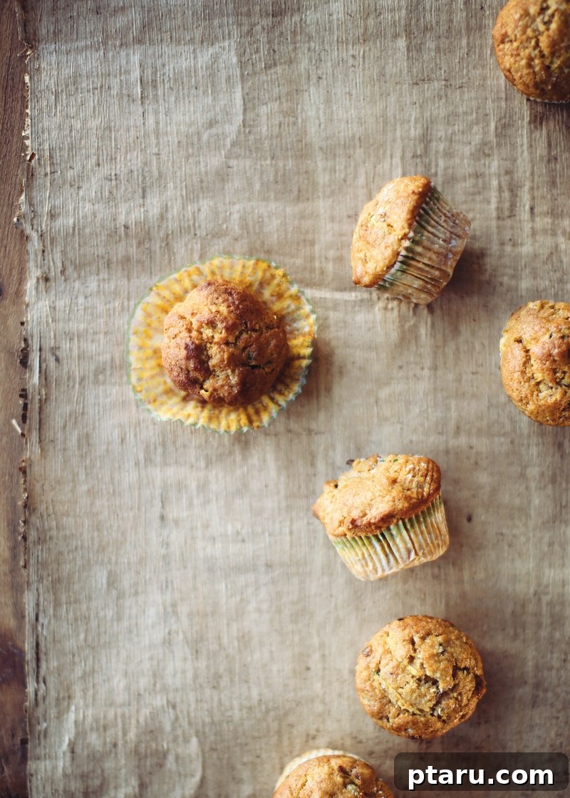 Tender Spiced Pumpkin Zucchini Muffins 6 A close-up of a stack of freshly baked zucchini pumpkin muffins on a countertop, ready to be enjoyed.