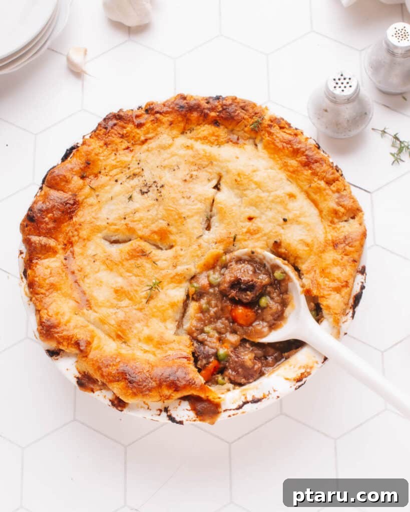Cozy Winter Comfort: 33 Hearty Casserole Creations 19 Hearty Beef pot pie with a spoon, revealing tender beef and vegetables in gravy.