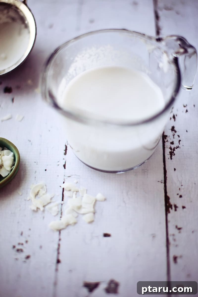 Fresh Coconut Milk From Scratch 5 A measuring cup filled with freshly made homemade coconut milk, showcasing its opaque, white color.
