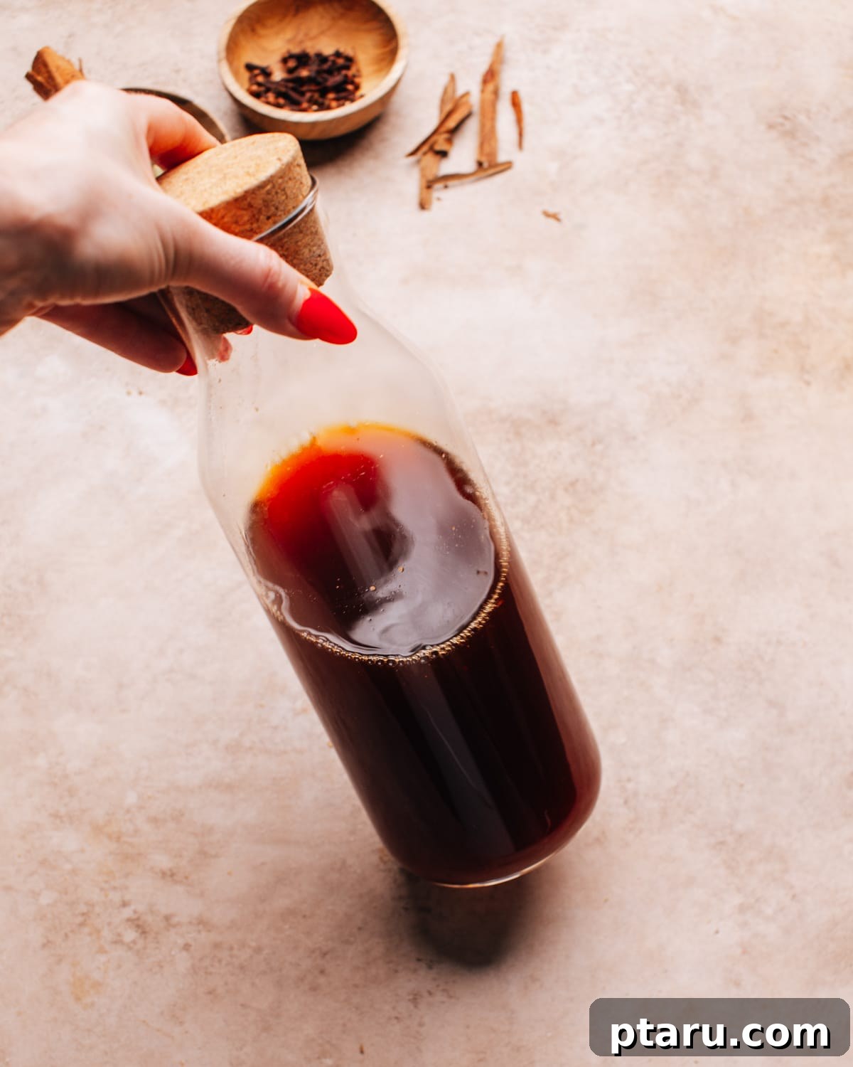 Brew Your Own Rich Chai Concentrate for Incredible Lattes 11 Tilting a glass bottle filled with homemade chai latte concentrate.