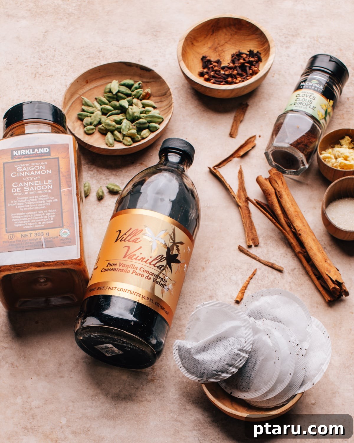 Brew Your Own Rich Chai Concentrate for Incredible Lattes 3 Assortment of chai concentrate ingredients: tea bags, cinnamon sticks, ginger, cloves, cardamom, vanilla, and sugar.