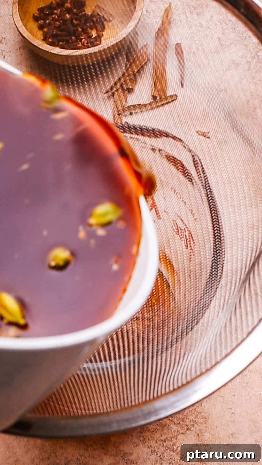 Brew Your Own Rich Chai Concentrate for Incredible Lattes 7 Straining homemade chai concentrate through a sieve into a glass measuring cup.