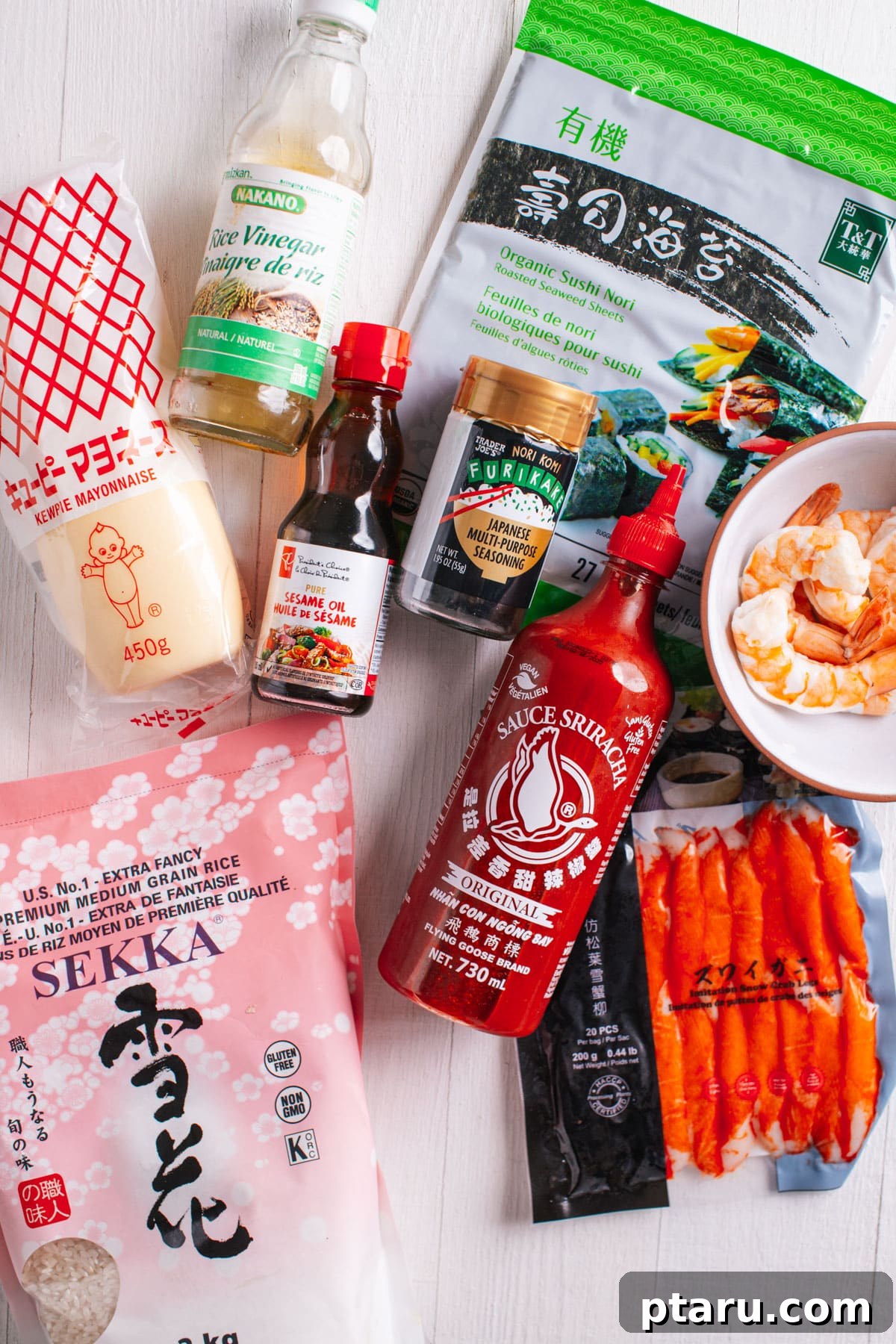 Viral TikTok Sushi Bake 3 A selection of fresh ingredients laid out for making sushi bake, including sushi rice, imitation crab, shrimp, mayonnaise, sriracha, and nori sheets.