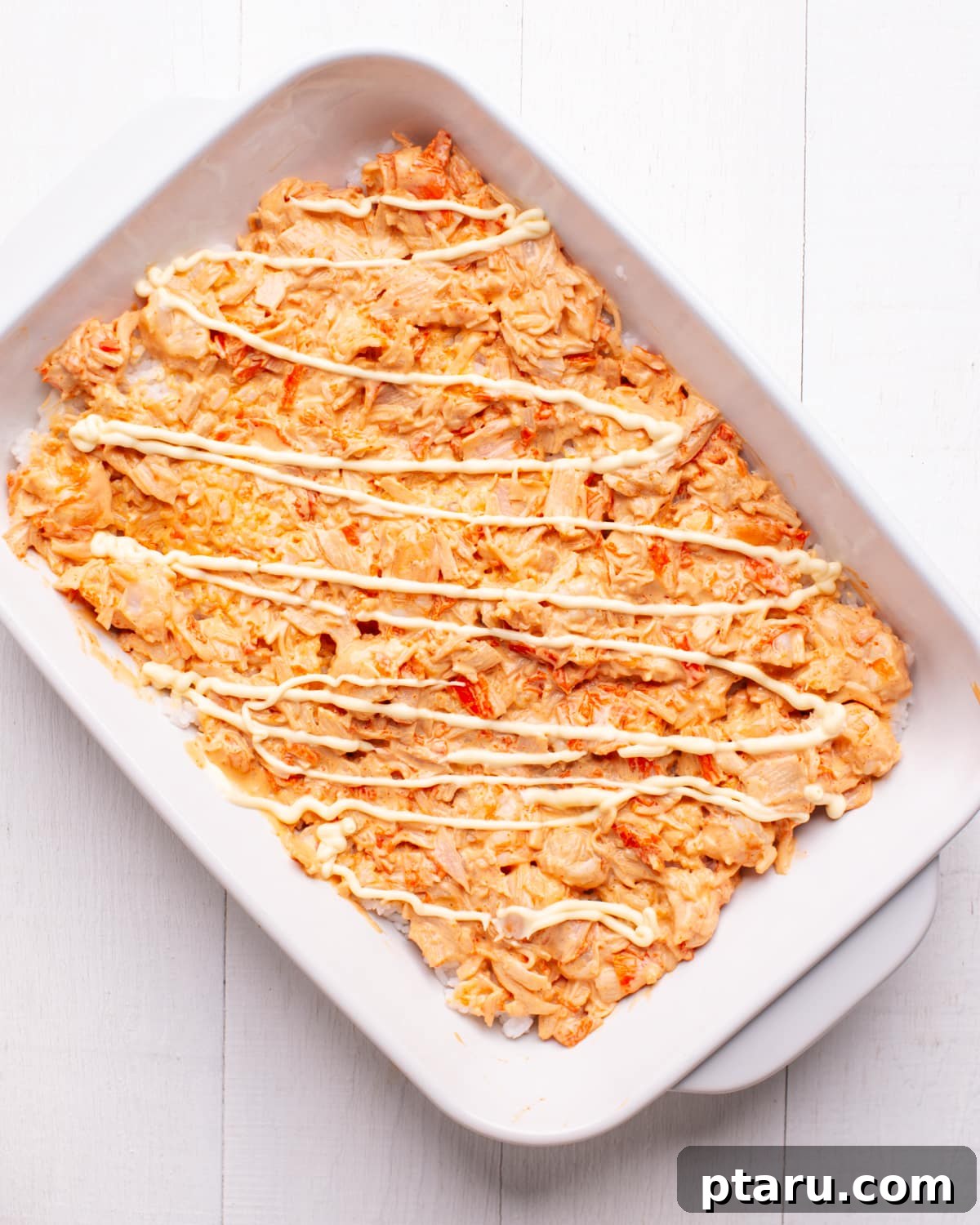 Viral TikTok Sushi Bake 6 Warm sushi rice being gently folded with a spatula in a bowl after adding the sushi vinegar mixture for seasoning.