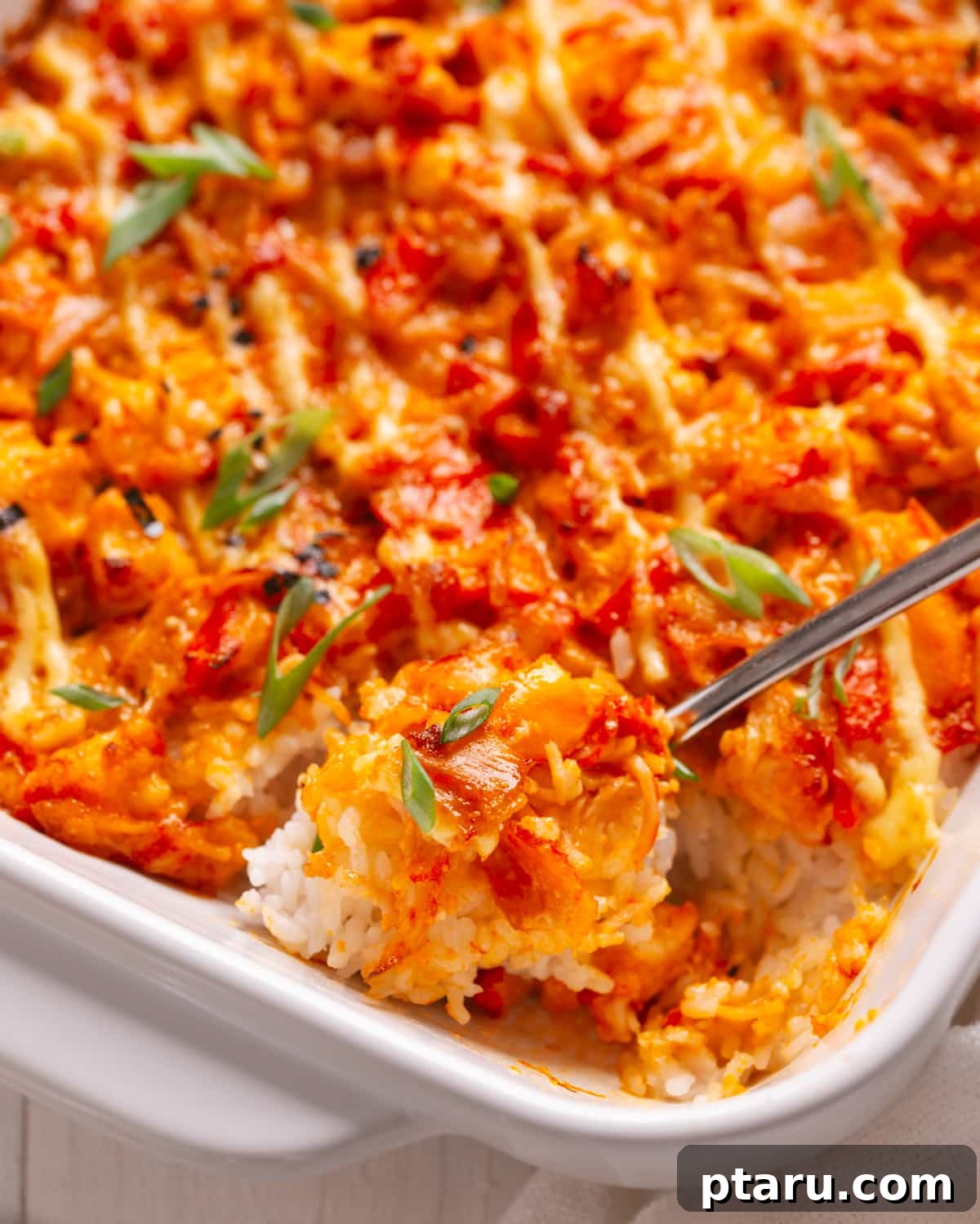 Viral TikTok Sushi Bake 8 A serving spoon scooping a portion of sushi bake from a large baking dish, showing the layers of rice and creamy topping.