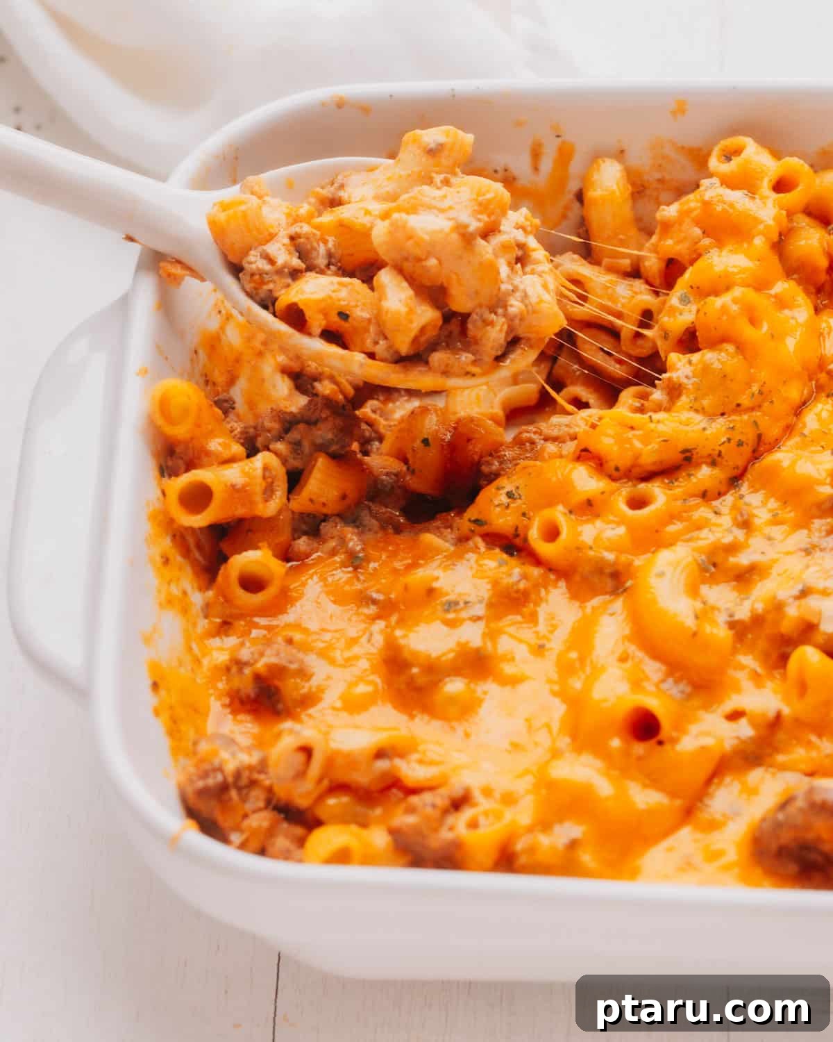 No-Fuss Cheeseburger Dinner 8 Lifting a spoonful of cheeseburger casserole. A close-up of a serving of cheeseburger casserole on a spoon, showcasing the rich texture and melted cheese.