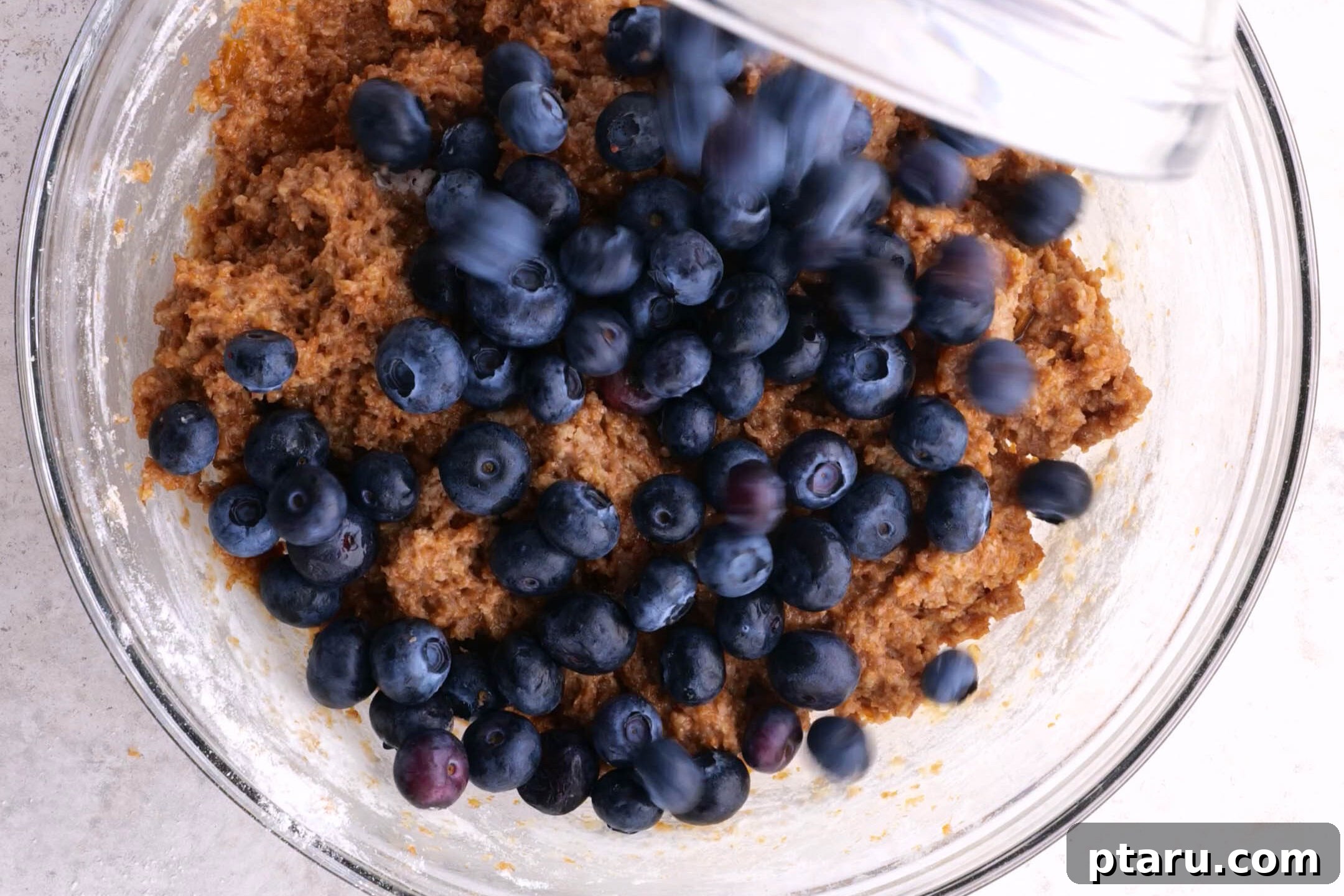 Classic Moist Blueberry Bran Muffins 4 Adding blueberries to the bran muffin batter, illustrating a key step.