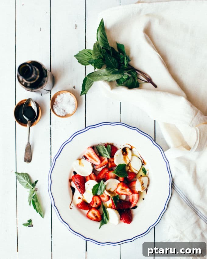 Strawberry Mozzarella Fresca 4 A collection of fresh ingredients for Caprese salad: a bowl of vibrant strawberries, fresh mozzarella balls, a bundle of green basil, and a bottle of extra virgin olive oil.