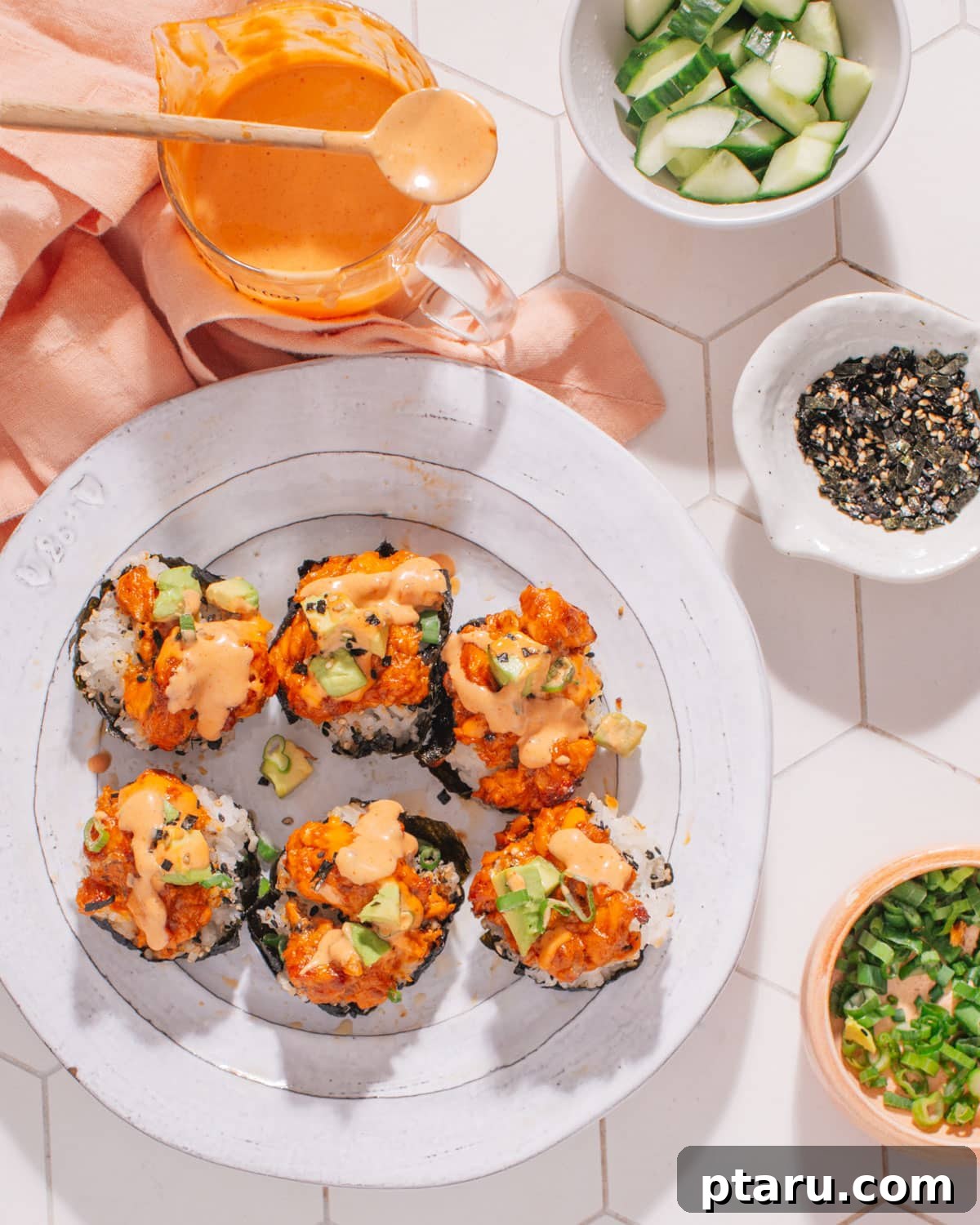 Baked Salmon Sushi Cups 6 Close-up of baked salmon rice muffins with a vibrant drizzle of spicy mayo and a garnish of green onions.