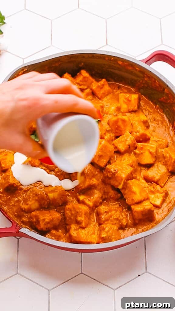 Creamy Butter Paneer 14 Drizzling heavy cream onto the finished Butter Paneer Masala in a serving bowl, creating beautiful swirls.